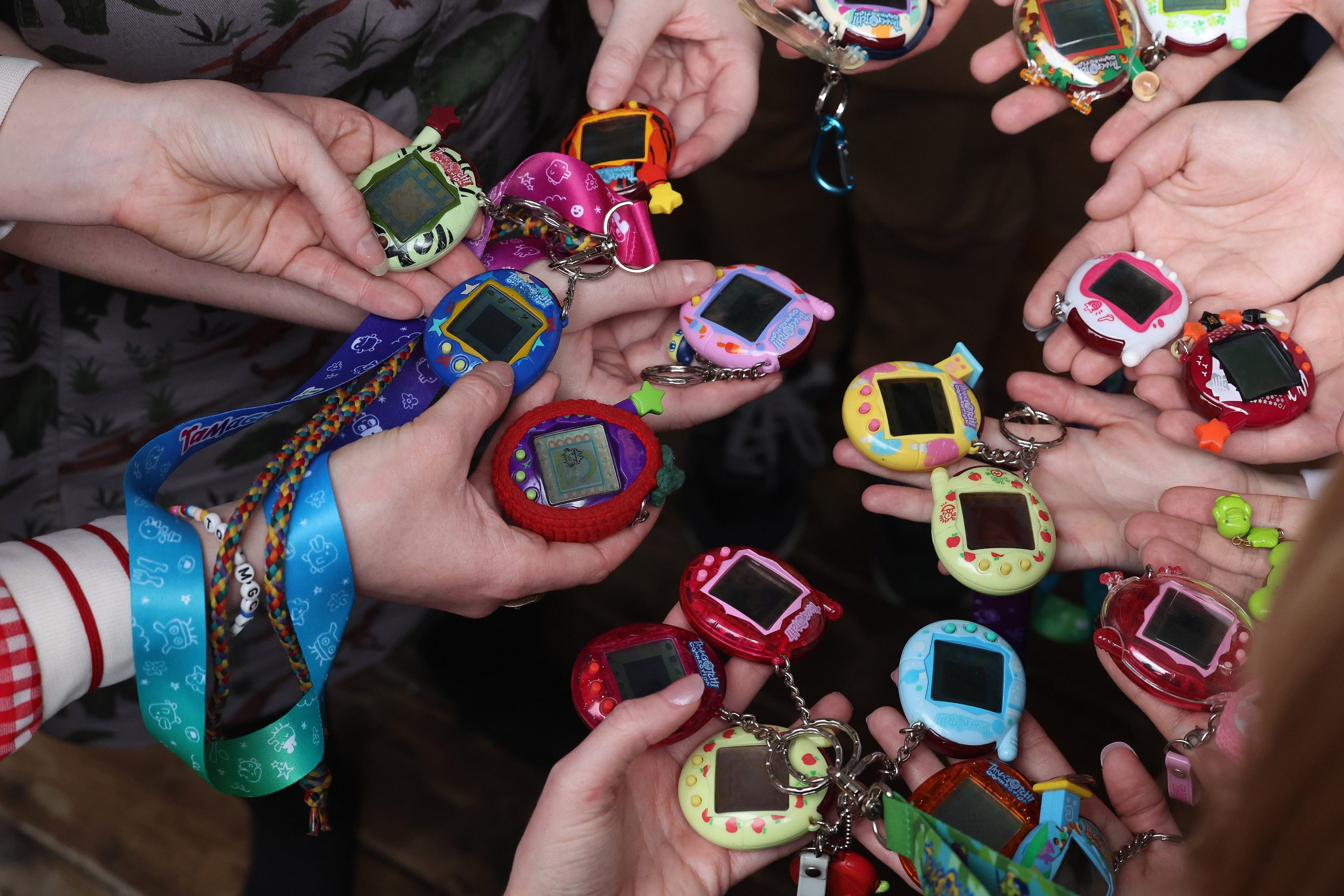 A photo of Toronto’s Tamagotchi Club hosting the first of many meetups the club hosts annually in Toronto on April 28, 2024. The image is a shot of people’s hands holding their Tamagotchis, which are small round electronic devices